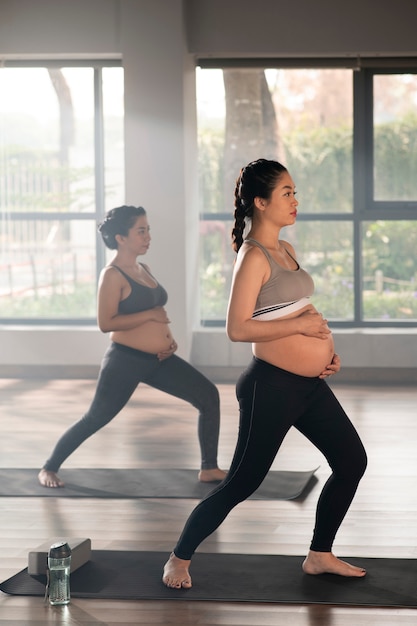 Foto grátis mulheres grávidas praticando ioga juntos