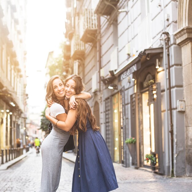 Mulheres jovens, abraçando, um ao outro, ficar, ligado, rua, cidade