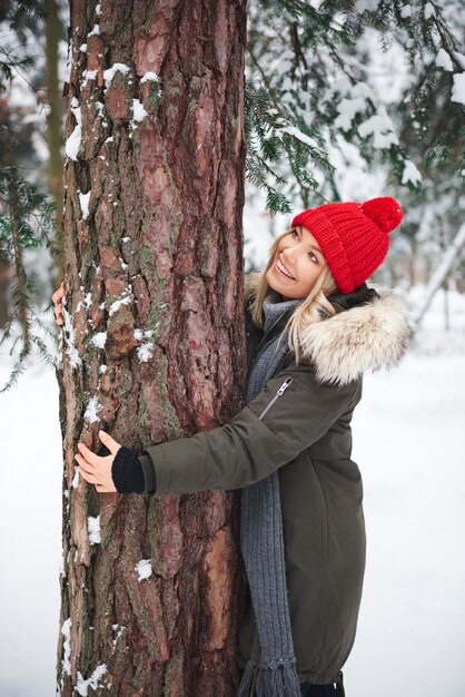 Mulheres jovens abraçando uma árvore na floresta de inverno