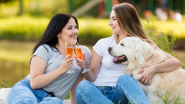 Mulheres jovens bebendo ao lado de um cachorro