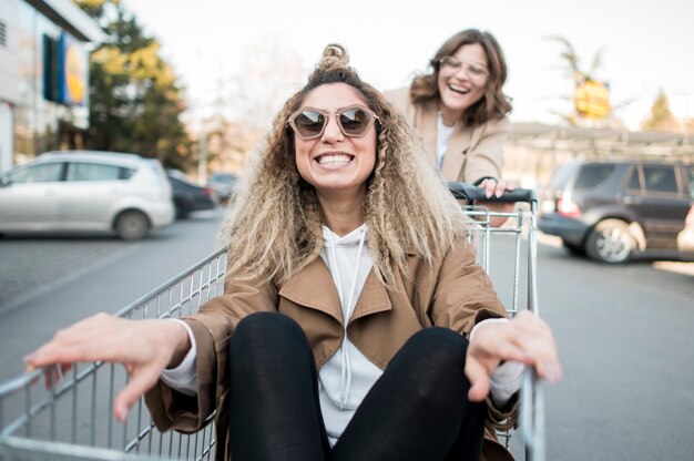 Mulheres jovens brincando com carrinho de compras