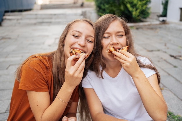 Mulheres jovens comendo pizza juntas fora