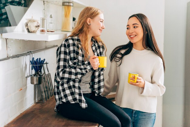 Mulheres jovens, conversando, em, cozinha