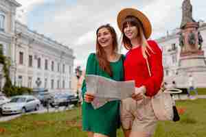 Foto grátis mulheres jovens elegantes viajando juntas na europa vestidas com roupas e acessórios da moda da primavera sorrindo amigos felizes se divertindo segurando o mapa