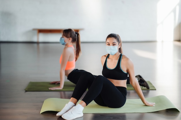 Mulheres jovens fazendo exercícios de flexão na sala durante a manhã