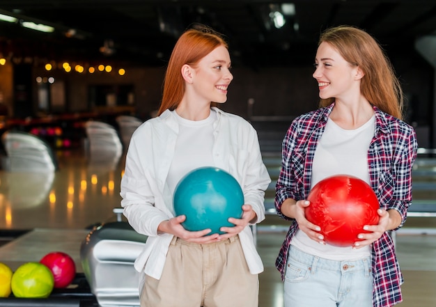 Mulheres jovens felizes segurando bolas de boliche coloridas