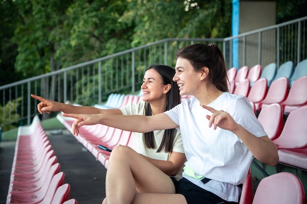 Foto grátis mulheres jovens magras em roupas esportivas sentadas nos assentos do estádio