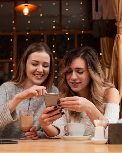 Mulheres jovens, olhando telefone