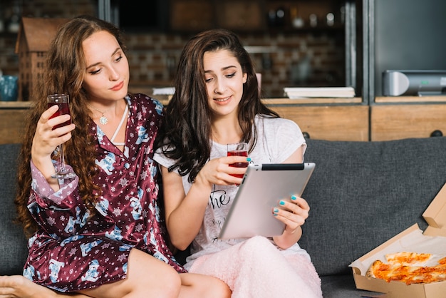 Mulheres jovens, sentar sofá, usando, tablete digital