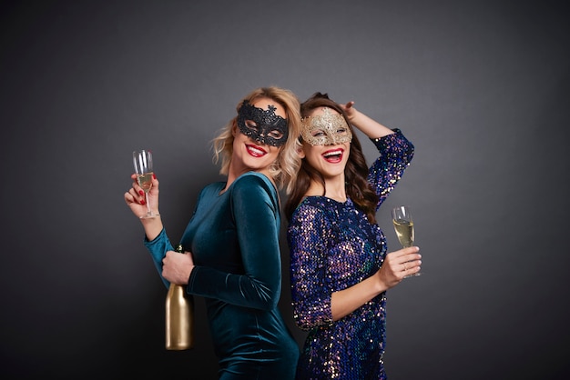 Mulheres mascaradas bebendo champanhe em estúdio