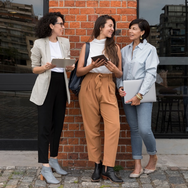 Mulheres modernas bonitas que trabalham ao ar livre