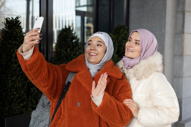 Foto grátis mulheres muçulmanas com hijabs tirando uma selfie e acenando enquanto estão de férias