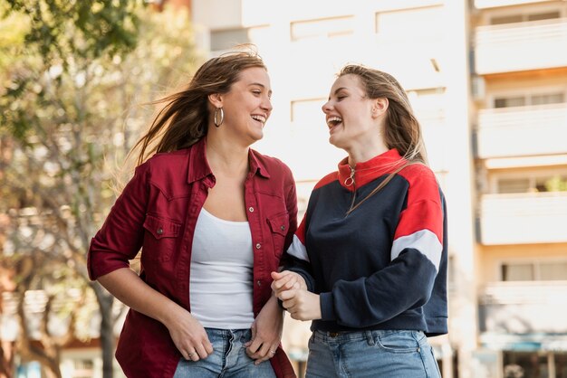 Mulheres na rua rindo um do outro