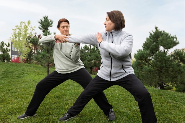 Mulheres praticando tai chi fora de tiro completo