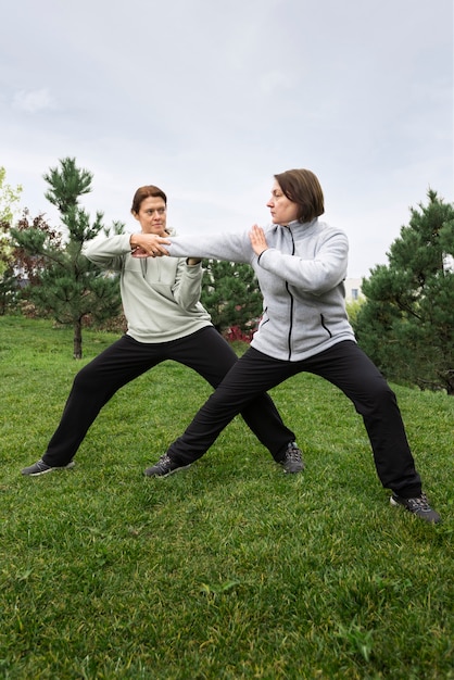 Foto grátis mulheres praticando tai chi tiro completo