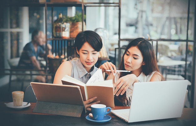 Mulheres que verific um caderno em um café