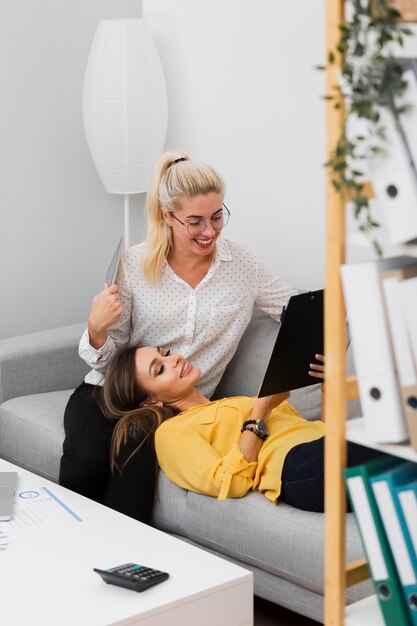 Mulheres relaxando em um sofá e olhando para uma prancheta