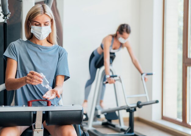 Mulheres se exercitando na academia com máscara médica