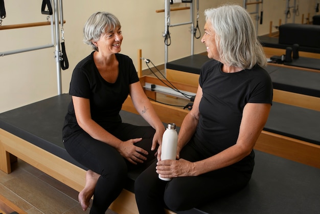 Mulheres seniores de alto ângulo na turma de reformadores de pilates