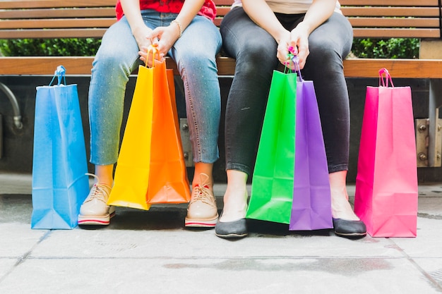 Mulheres, sentando, ligado, banco, com, bolsas para compras