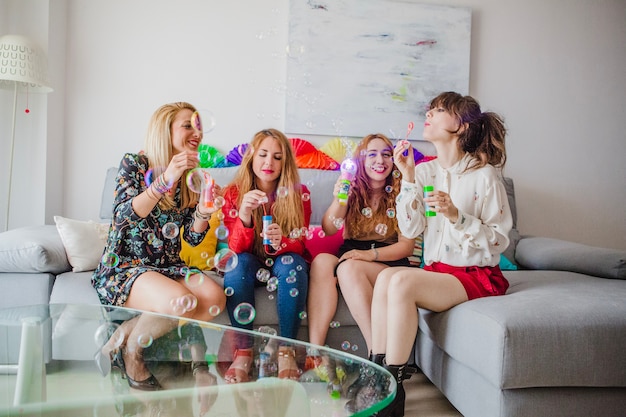 Mulheres soprando bolhas no sofá
