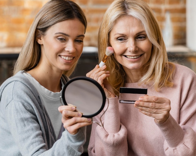 Mulheres sorridentes a maquiar-se em casa
