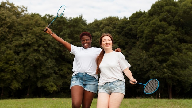 Mulheres sorridentes ao ar livre com raquetes