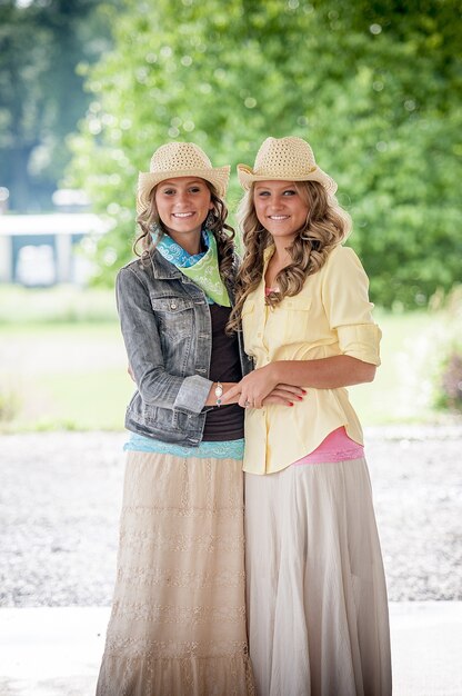 Foto grátis mulheres sorridentes com chapéus e vestidos coloridos em um parque sob a luz do sol