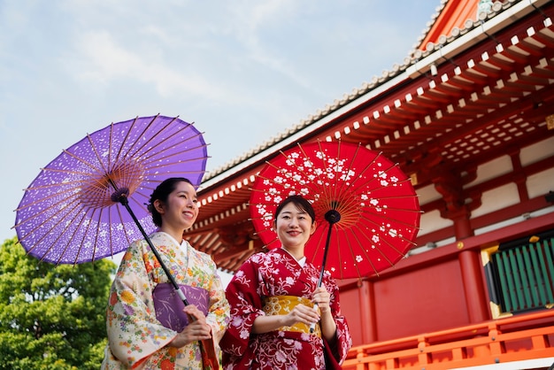Foto grátis mulheres sorridentes de baixo ângulo segurando guarda-chuva wagasa