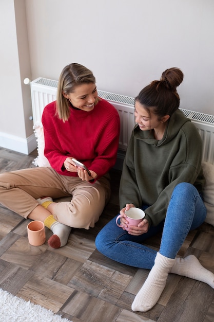 Mulheres sorridentes de tiro completo com xícaras de café dentro de casa