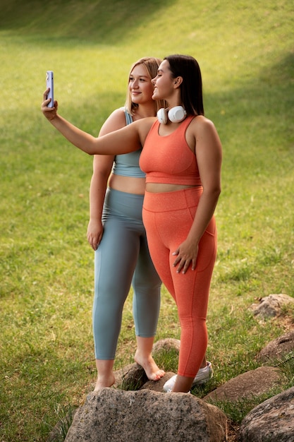 Foto grátis mulheres sorridentes de tiro completo tomando selfie