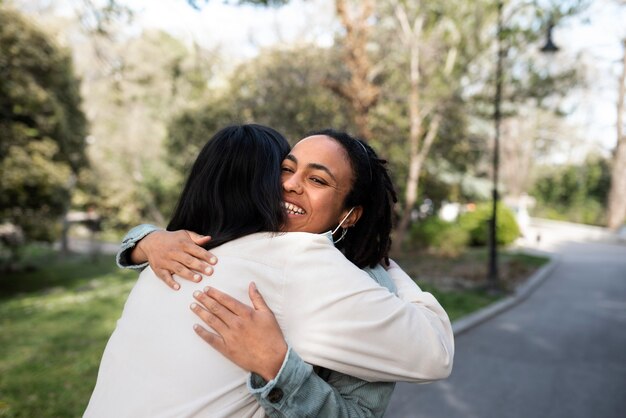 Mulheres sorridentes de tiro médio abraçando ao ar livre