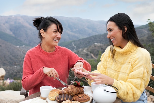 Mulheres sorridentes de tiro médio com comida saborosa