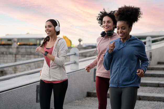 Mulheres sorridentes de tiro médio correndo juntas