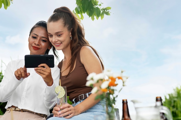 Mulheres sorridentes de tiro médio olhando para o telefone