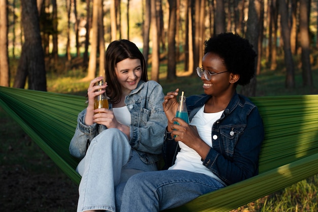 Mulheres sorridentes de tiro médio sentadas em redes