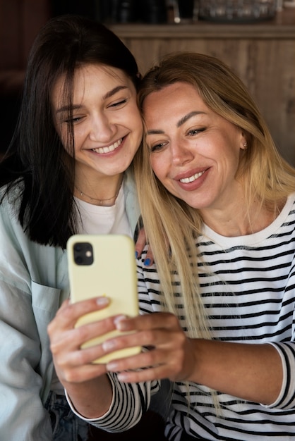 Mulheres sorridentes de vista frontal segurando smartphone