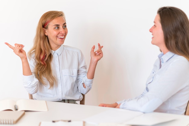 Mulheres sorridentes se comunicando através da linguagem de sinais