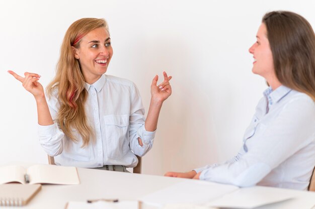 Mulheres sorridentes se comunicando através da linguagem de sinais