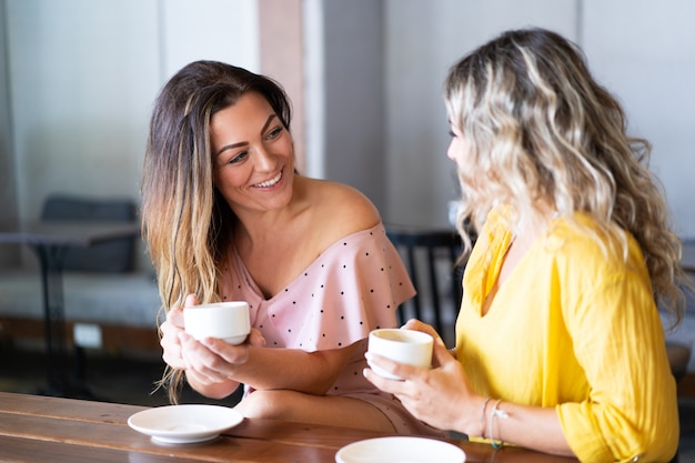 Mulheres sorridentes se divertindo e bebendo café no café