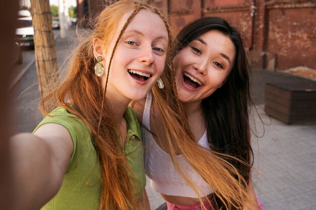 Mulheres sorridentes tomando selfie vista frontal