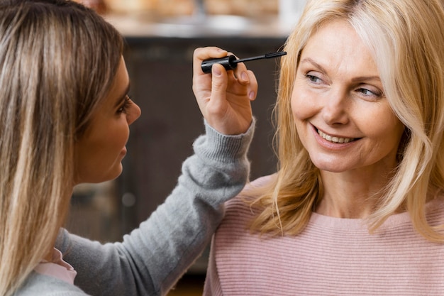 Mulheres sorridentes usando rímel em casa