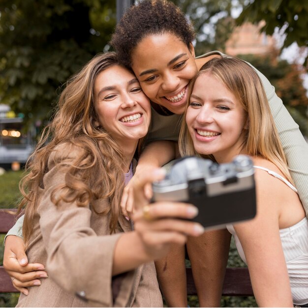 Mulheres tirando uma selfie com uma câmera retro
