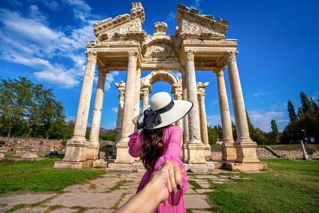 Mulheres turistas segurando a mão do homem e levando-o à antiga cidade de Afrodisias, na Turquia.