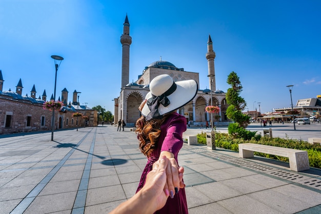 Mulheres turistas segurando a mão do homem e levando-o à mesquita em Konya, na Turquia.