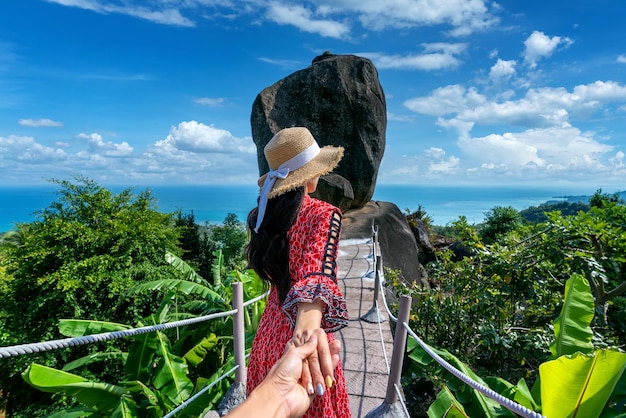 Mulheres turistas segurando a mão do homem e levando-o a sobrepor pedra em Koh Samui Tailândia