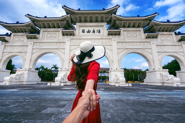 Foto grátis mulheres turistas segurando a mão do homem e levando-o ao memorial de chiang kai shek em taipei, taiwan.