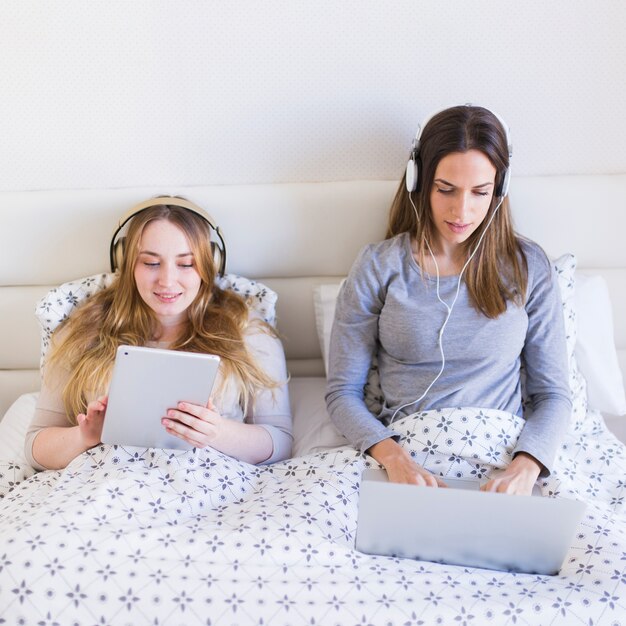 Mulheres usando tecnologias na cama