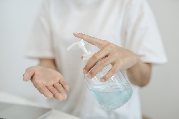 Mulheres vestindo camisas brancas que pressionam o gel para lavar as mãos e limpar as mãos.