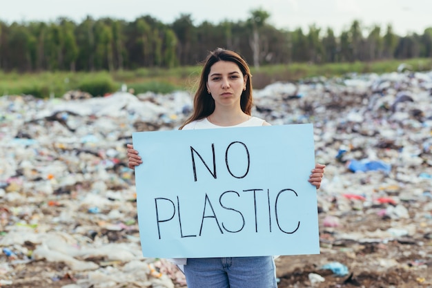 Mulheres voluntárias fazem piquete em aterro sanitário com um pôster sem plástico, ativista luta contra a poluição ambiental